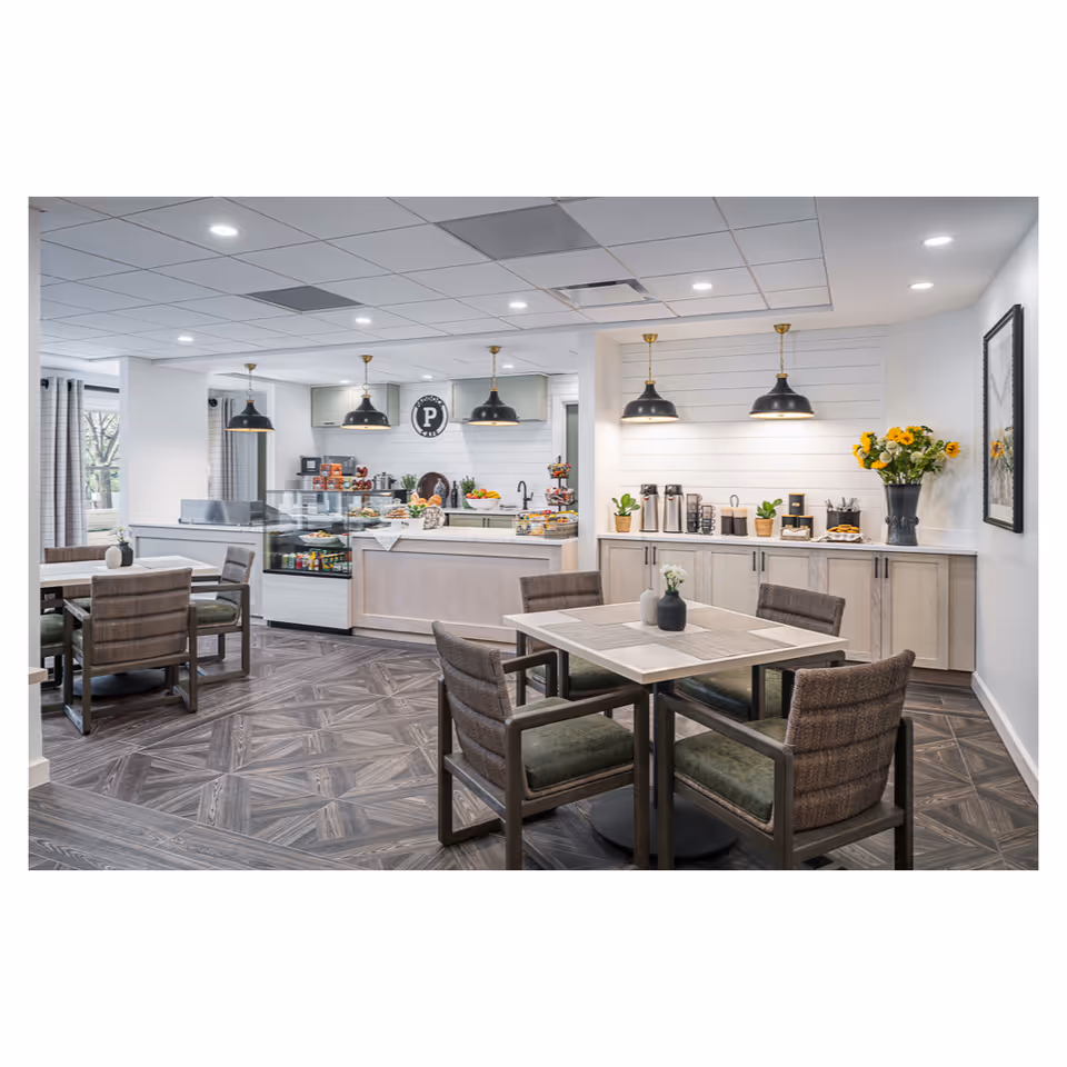 Open dining area with tables and upholstered chairs, pendant lights, and a cafe-style serving counter with a coffee station.