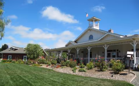Sunny exterior of Magnolia Gardens senior living facility with a porch and landscaped garden.