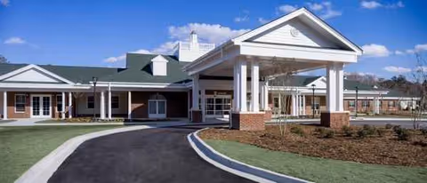 Exterior view of Estates Healthcare & Rehab Center with a covered entrance and landscaped roundabout.