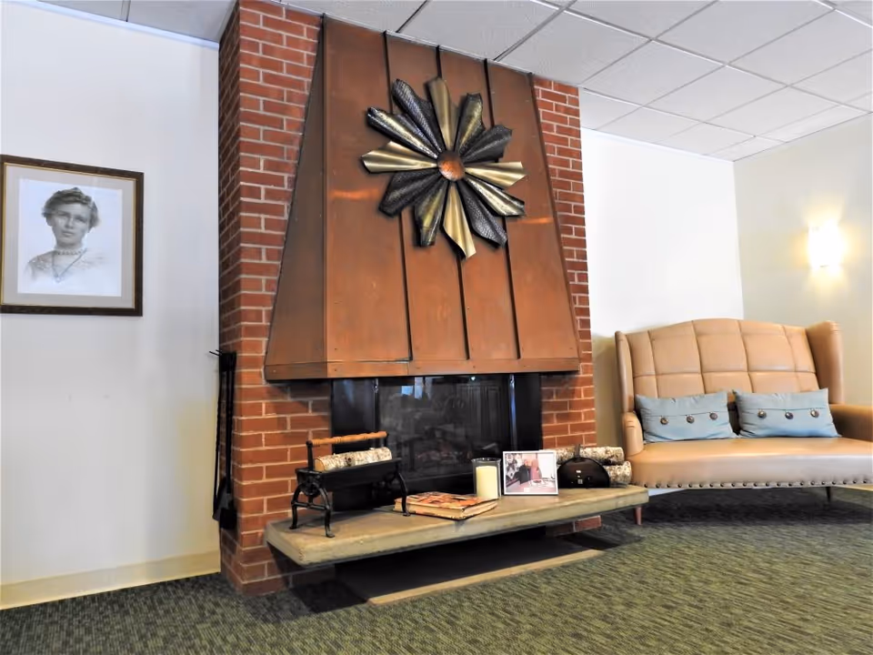 A lounge area with a brick fireplace topped by a decorative metal wall sculpture and an upholstered sofa.