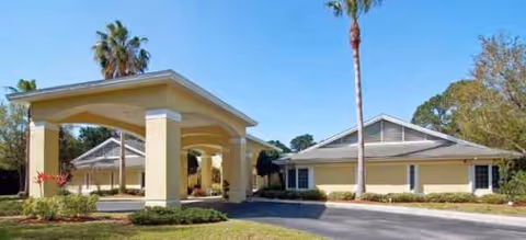 Brookdale Deer Creek Sarasota exterior with a covered entrance and palm-lined driveway.