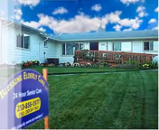 Single-story senior care building with a manicured lawn and a yard sign reading "Blessing Elderly Care" under a blue sky.