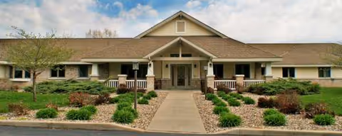 Single-story senior living facility exterior with landscaped entrance and central front steps.