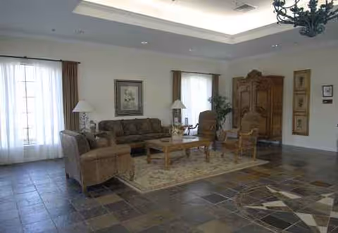 Bright lounge area with seating, coffee table, lamps, rug, and large armoire.