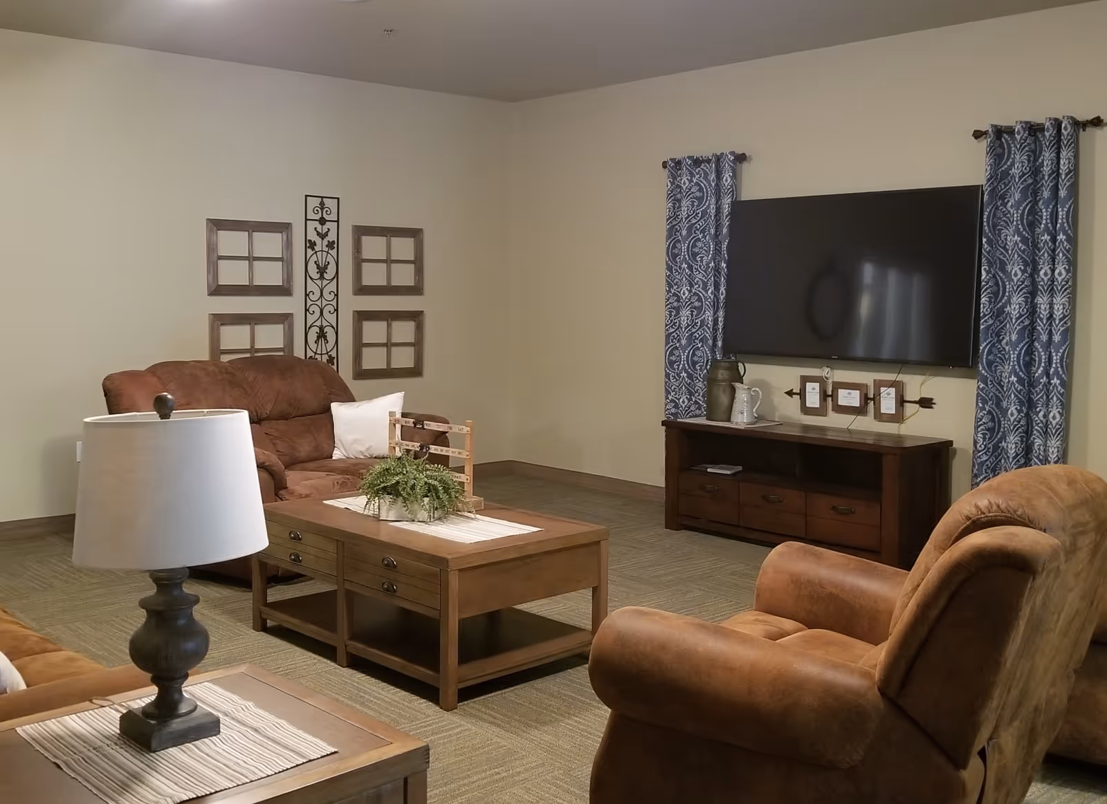 Cozy living room with brown recliner chairs and sofa, a wooden coffee table, wall-mounted TV, and decorative wall accents.