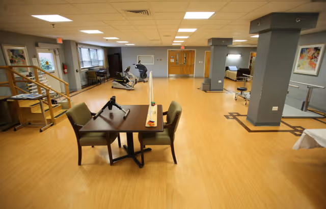 Spacious interior therapy/Activity room with exercise equipment, a table and chairs, and therapy stations.