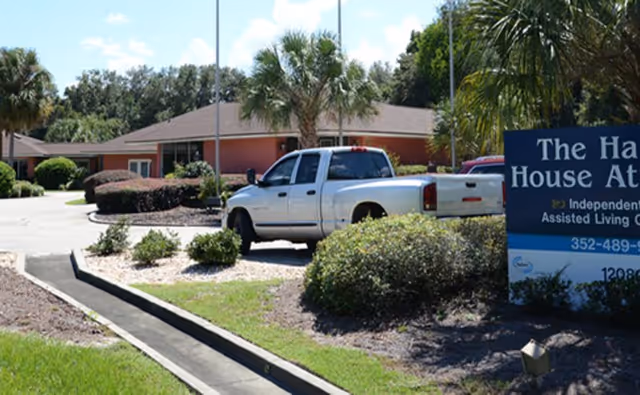 Front view of Harbor House of Ocala showing a pickup truck parked near the facility entrance, landscaping, and a blue entrance sign.