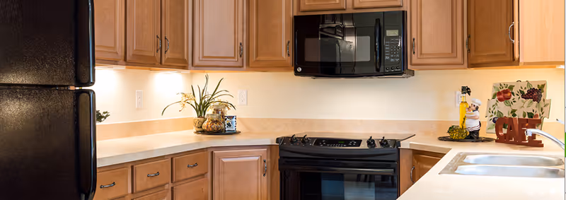 Bright Mount Joy Country Homes kitchen with wooden cabinets, appliances, and a double sink.