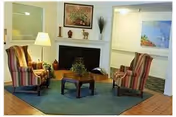 Cozy seating area with two striped armchairs, a small coffee table, and a fireplace with artwork above.
