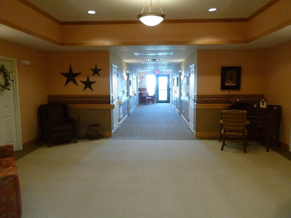 Carpeted interior hallway and sitting area with chairs, decorative stars on the wall, and a desk leading to a glass exit door.