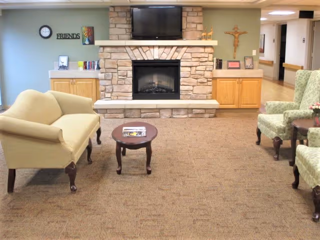 Cozy common room with a stone fireplace and TV, sofas and armchairs around a small coffee table.