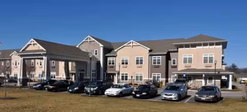 Exterior view of Brookdale Centre of New England with parked cars.