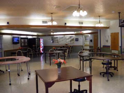 Empty dining area in Mansfield Nursing Center with round tables, chairs, and a central vase.