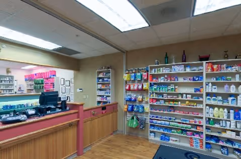 Interior of a small retail shop at a senior living community with a service counter and shelves stocked with toiletries, snacks, and household items.