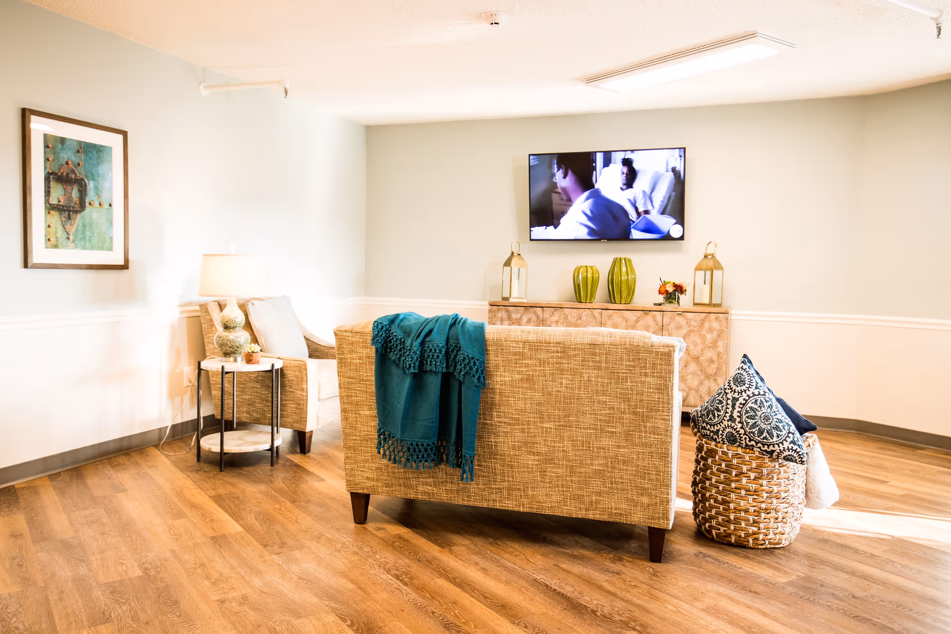 Bright common living room with a couch, armchair, wall-mounted TV and decorative accents.