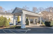 Exterior view of Sterling Care Bethesda with a covered entrance and parked cars.