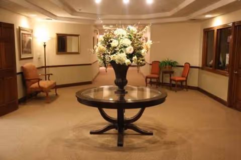 Indoor lobby seating with a round central table and a large floral arrangement.