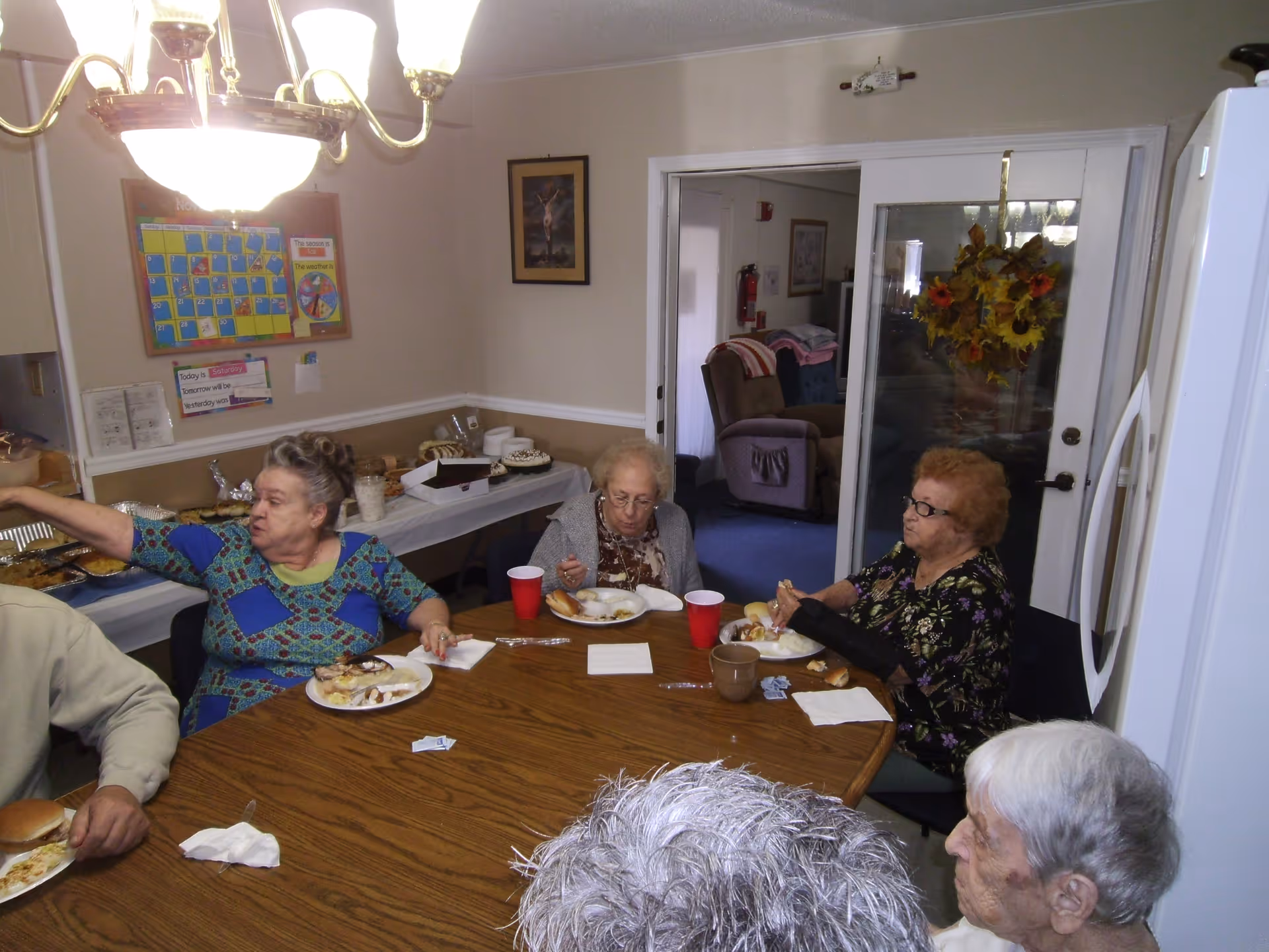 Several residents sitting around a dining table in a communal room eating a meal.