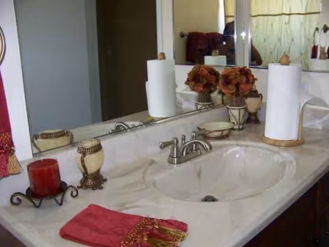Bathroom vanity with sink, faucet, mirror, towels, and decorative flowers.