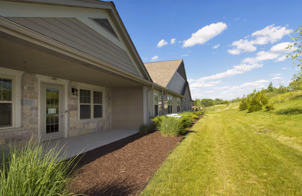 Exterior view of Sunrise Meadows Senior Living with a long lawn and building facade.