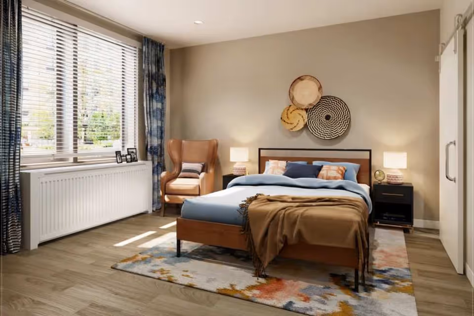 Sunlit bedroom with a bed, bedside tables, an armchair, decorative wall baskets, and a window with blinds.