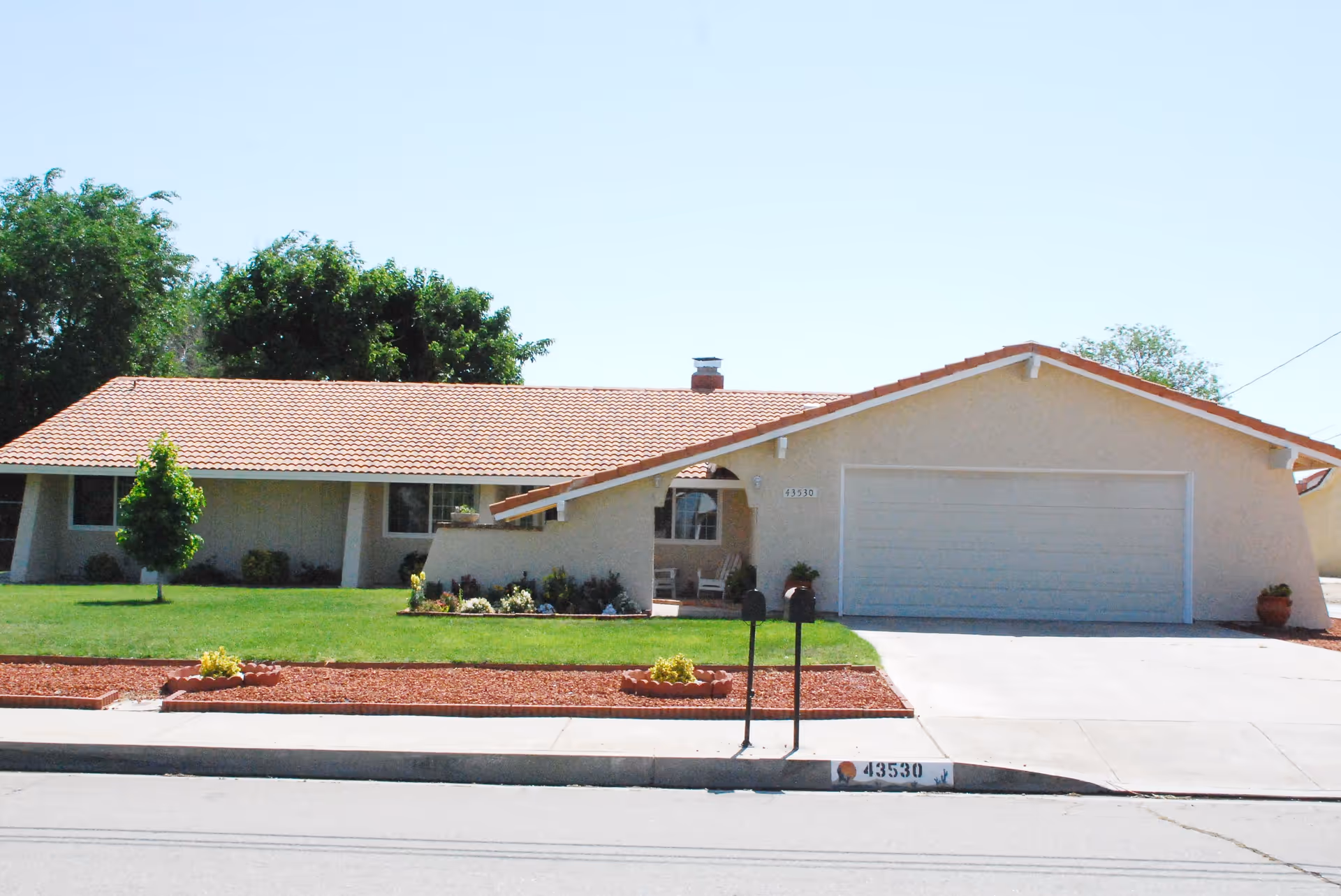 Single-story ranch-style house with a tiled roof, attached two-car garage, driveway and front lawn.