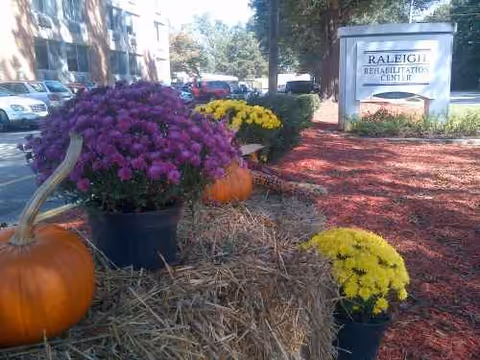 Exterior view of Raleigh Rehabilitation Center with pumpkins, mums, and hay bales decorative arrangement.