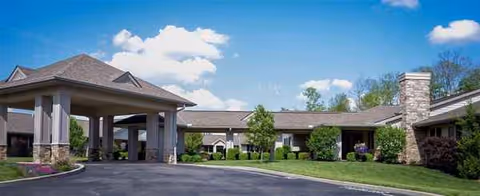 Exterior view of Woodland Country Manor with covered entrance, stone columns, and landscaped grounds.