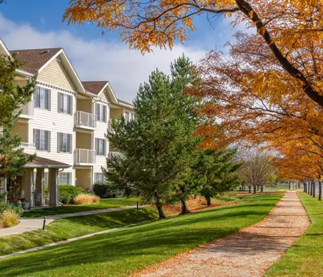 Exterior view of Sugar Valley Estates with a tree-lined path and residential buildings.