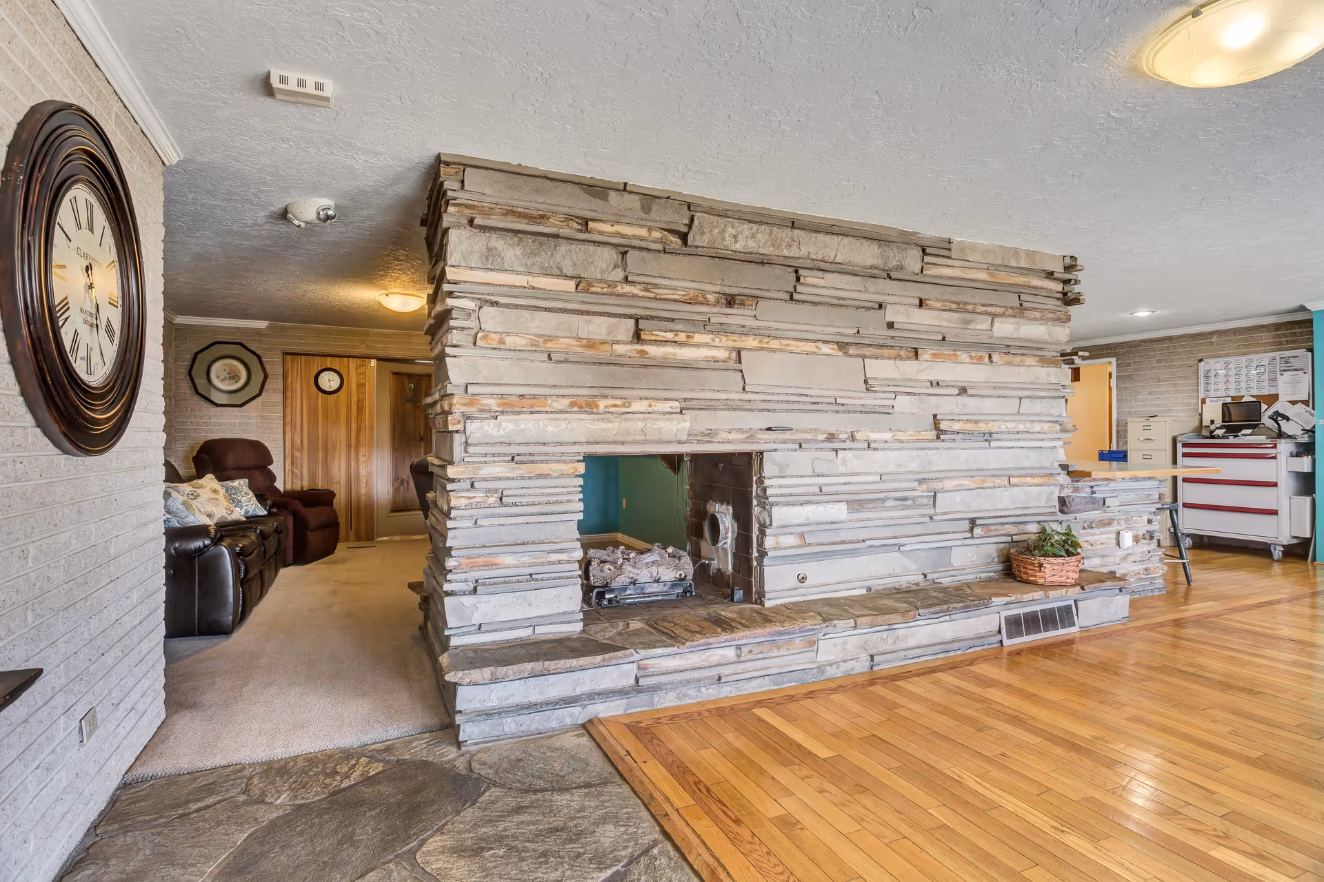 Interior common area featuring a large stacked-stone double-sided fireplace, hardwood floors, and seating.
