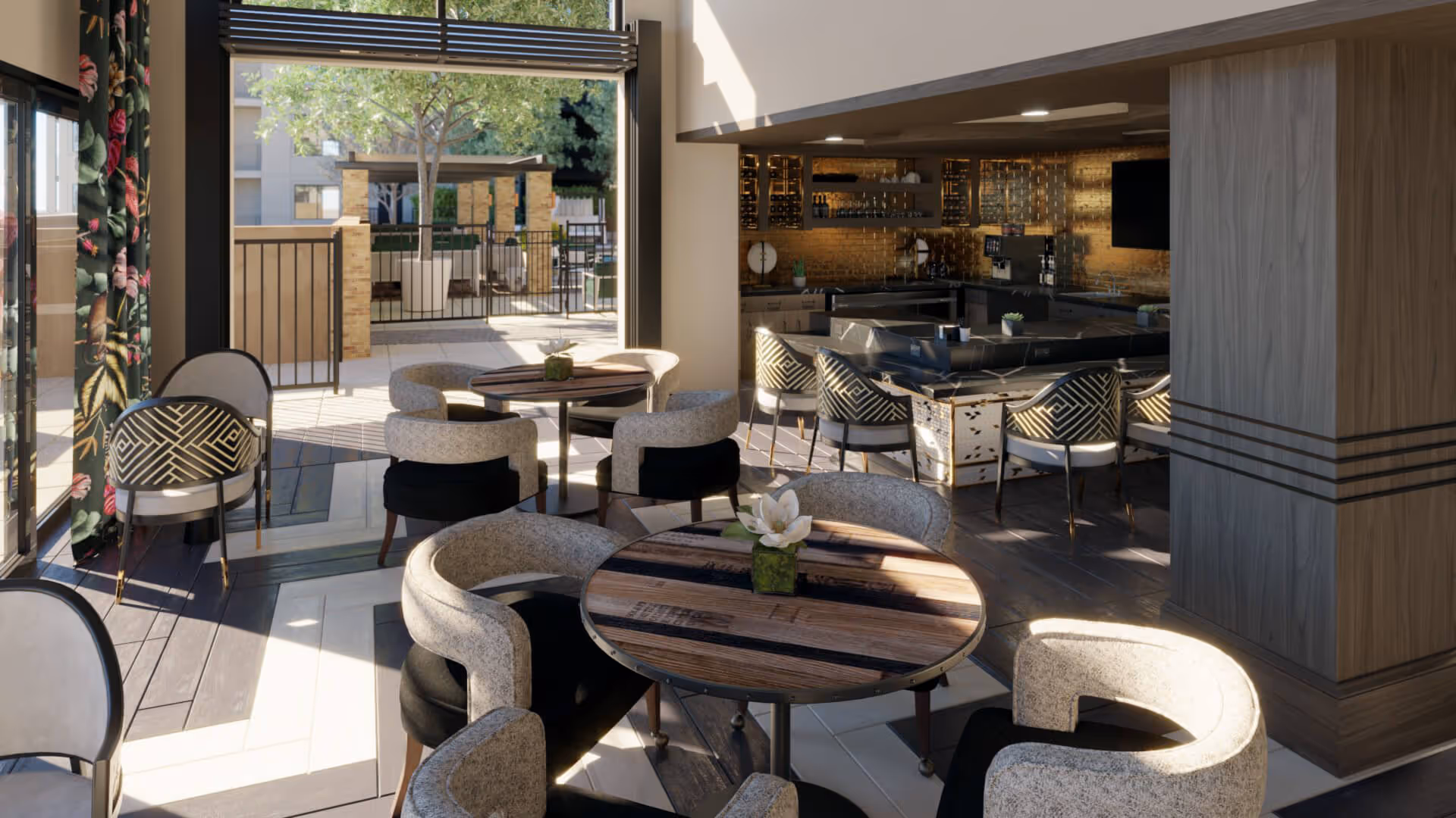 A modern indoor seating area with round wooden tables and cushioned chairs, adjacent to an outdoor patio with additional seating and greenery. The interior features a bar with high chairs and warm lighting, and large windows allowing natural light to fill the space.
