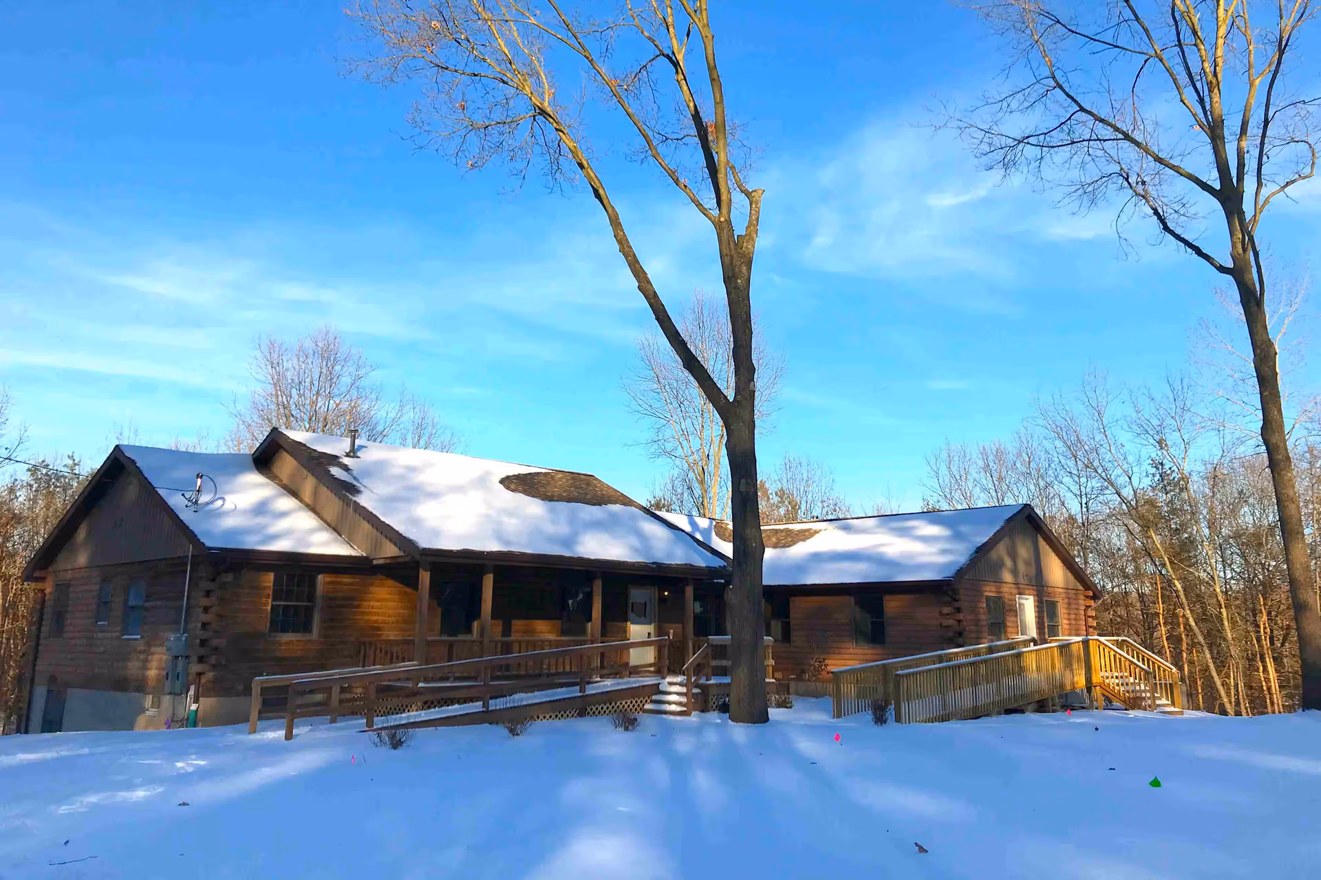 Snow-dusted wooden senior living facility exterior with ramps and leafless trees