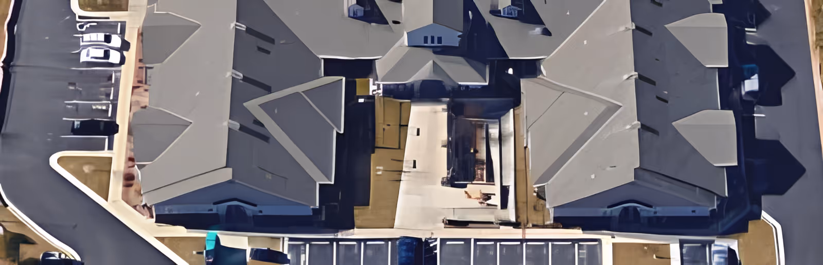 Aerial view of Victoria Falls Skilled Nursing facility showing multiple connected buildings with gray roofs, surrounding parking areas, and driveways.