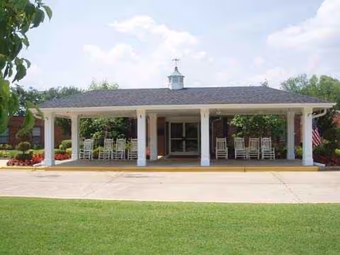 Front view of Maplewood Health Care Center with a covered entrance and rocking chairs.