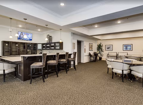 Spacious communal dining and lounge area with a bar, high stools, and round tables with chairs.