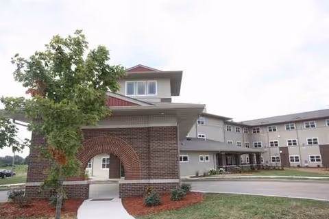 Exterior view of Prairie Living at Chautauqua facility with brick arch entry and greenery.