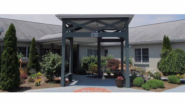 Exterior view of Whispering Pines entrance with landscaped garden and benches.