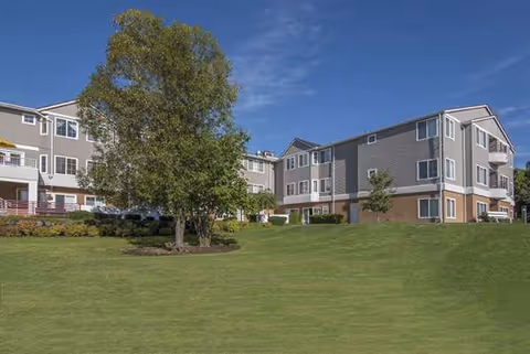 Liberty Shores Assisted Living exterior buildings on a sloped green lawn under blue sky.