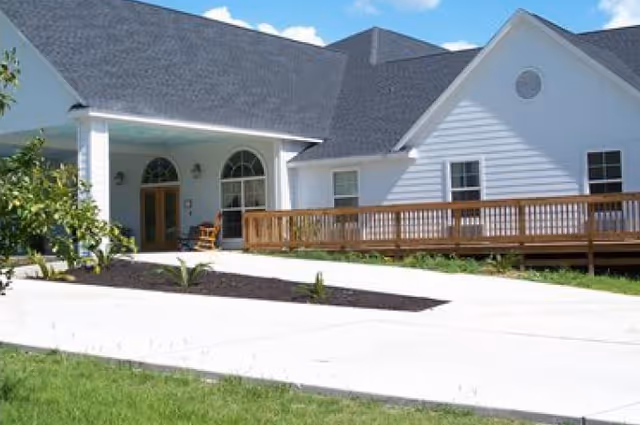 White, single-story senior living facility with a wooden ramp and front entrance.