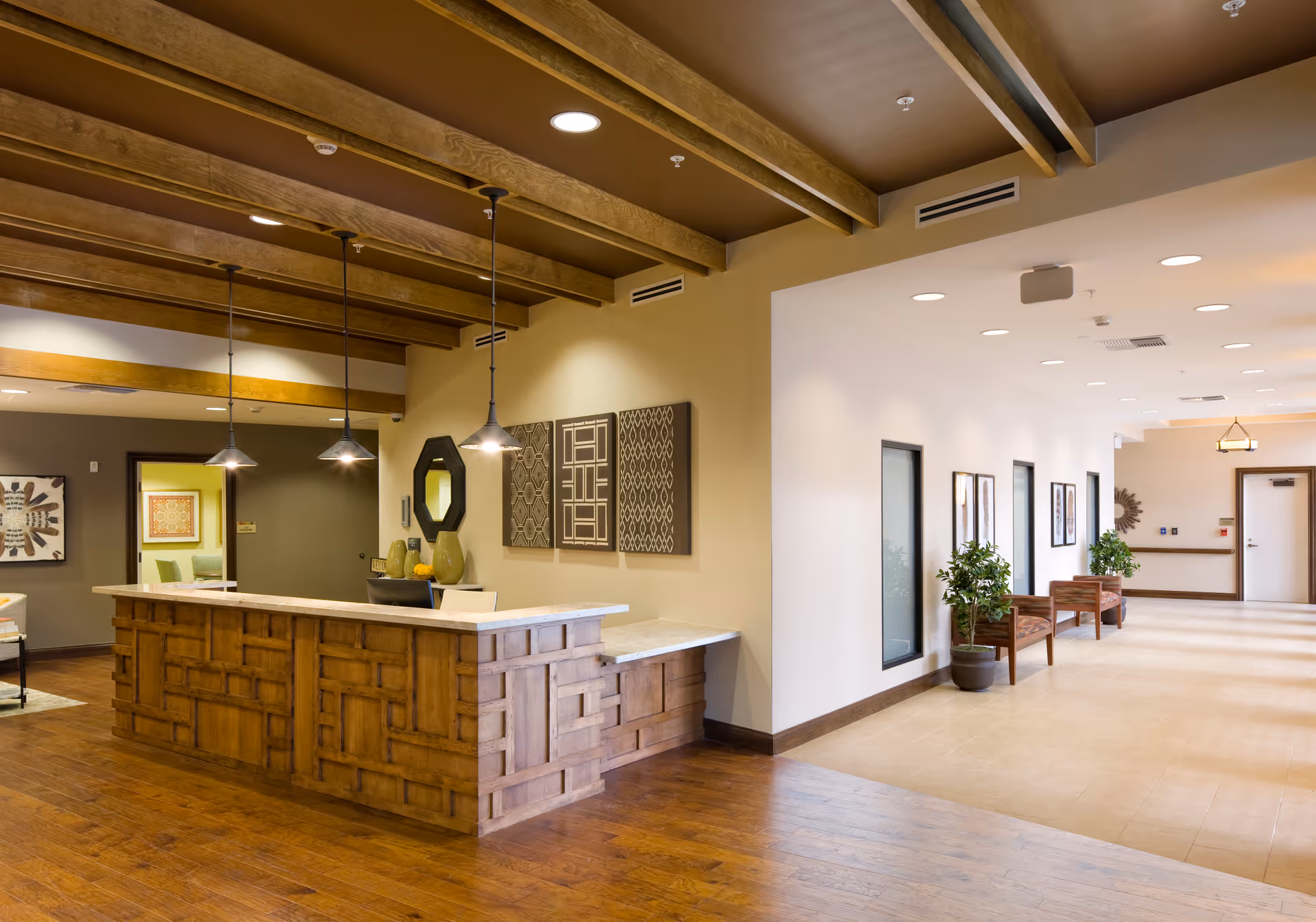 Lobby reception area with a wooden front desk, pendant lights, seating and decorative wall art.