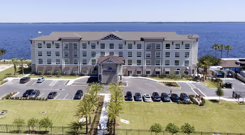 A Marina Isle Waterfront Assisted Living building with a parking lot and palm trees.