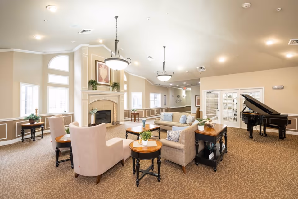 Bright, spacious communal living room with seating area, fireplace, and a grand piano.