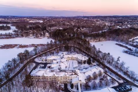 Aerial winter view of Maplewood at Weston campus surrounded by snow-covered trees.