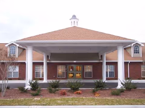 Brick senior living facility with a covered portico entrance and landscaped front.