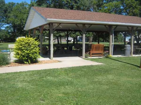 Shaded pavilion with benches and picnic tables on a grassy lawn at La Plata Nursing Home.