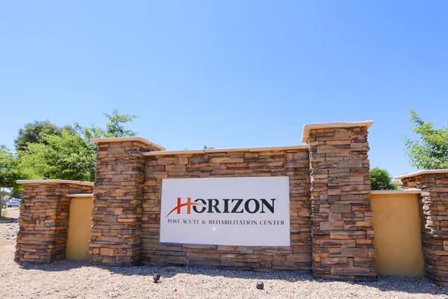 Stone entrance sign for Horizon Post Acute and Rehabilitation Center under a clear blue sky with some greenery in the background.