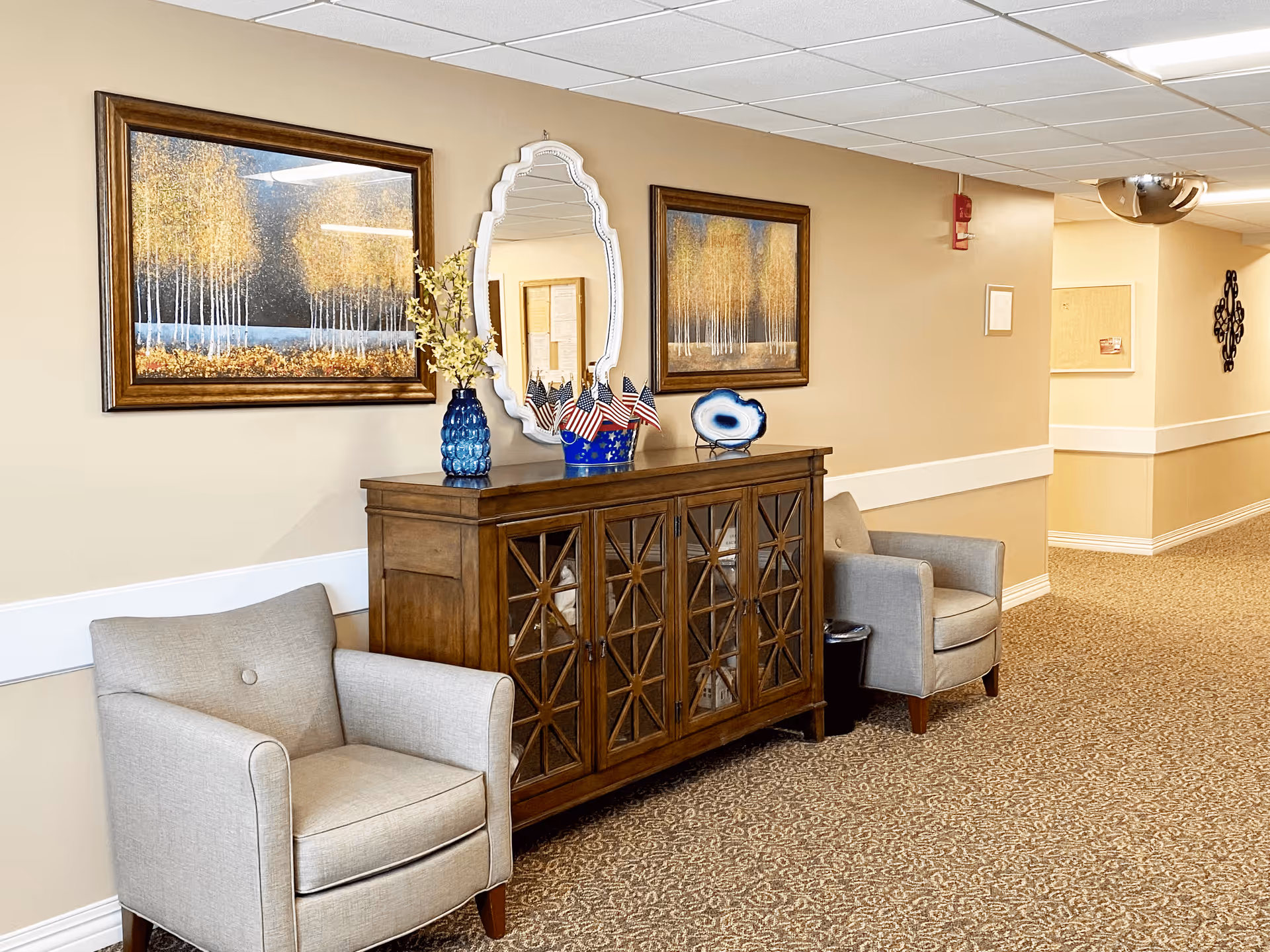 Hallway seating area with two armchairs, a wooden console table with decorative items, and framed artwork on the wall.