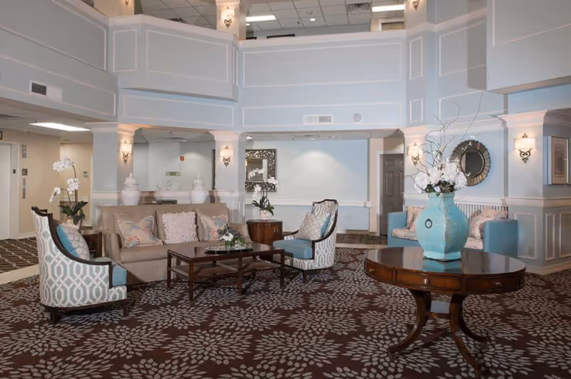 Spacious furnished lobby/lounge with sofas, armchairs, coffee tables, and a large decorative vase on a round table.