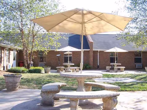 Outdoor courtyard with stone seating and large umbrellas near a brick building.