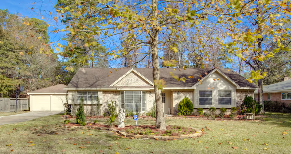 Single-story residential-style senior care facility front with lawn, trees, and driveway.